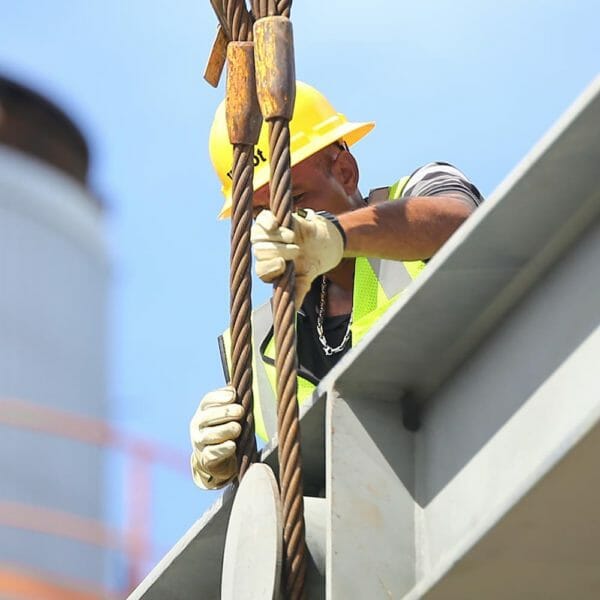 worker in a hardhat adjusting crane rigging